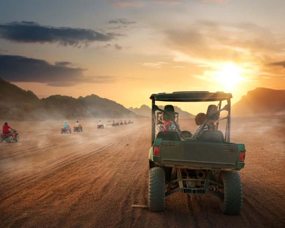 People driving dune buggies in desert