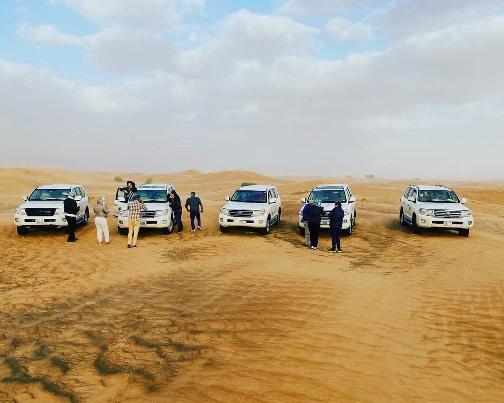 People are standing in front of their vehicles